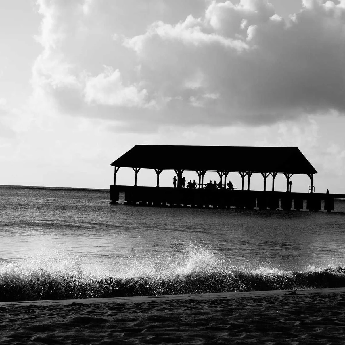 Beach Pier Pavilion Silhouette Black and White Black and white silhouette of beach pavilion pier with people against ocean and cloudy sky